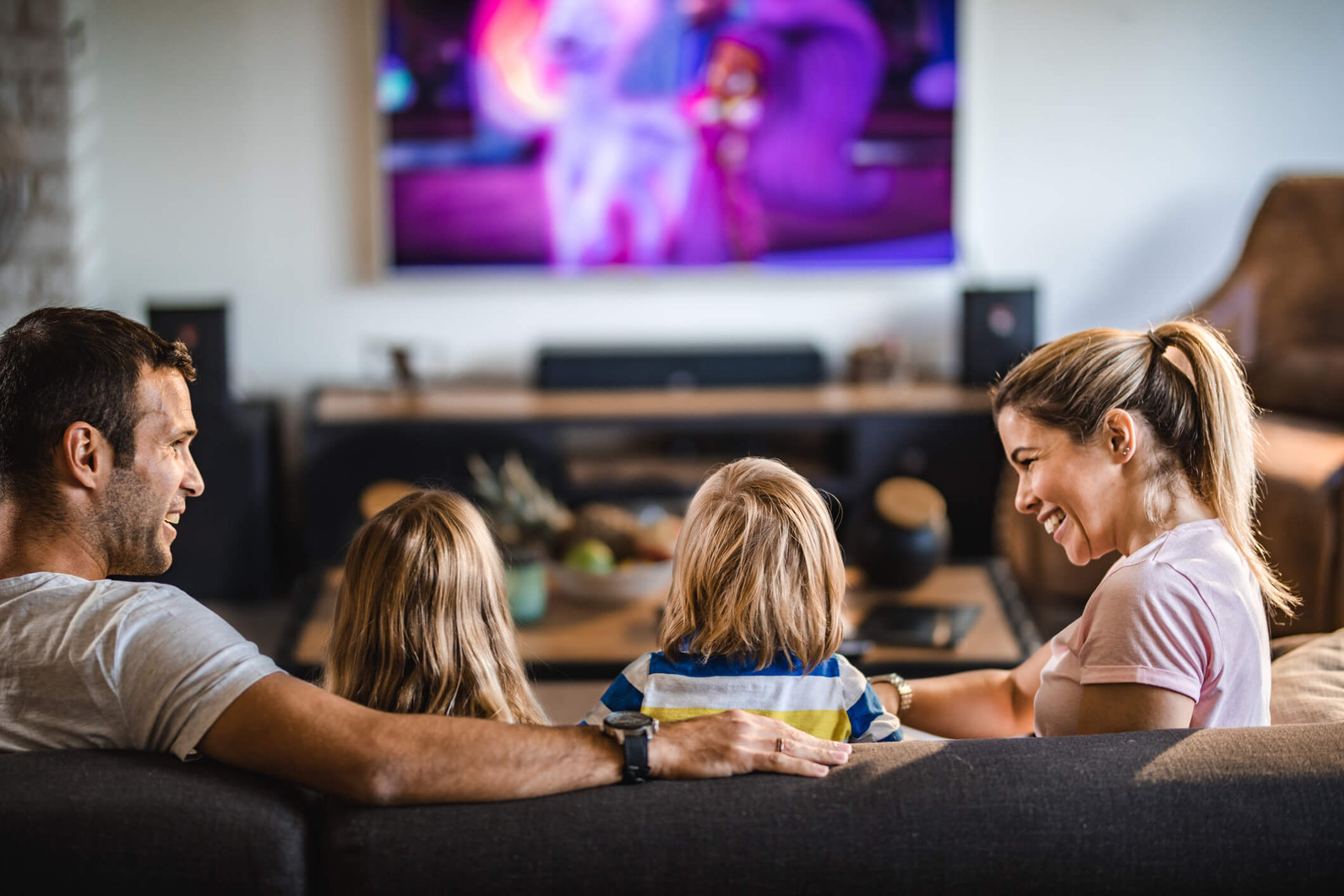 Mom-dad-daughter-and-son-sitting-on-living-room-couch-watching-TV-1 (1) Mom Dad Daughter And Son Sitting On Living Room Couch Watching Tv 1 (1)