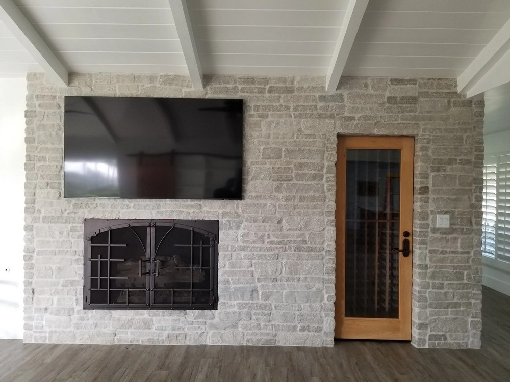 TV mounted over a stone fireplace, home theater installation by Low Voltage Components